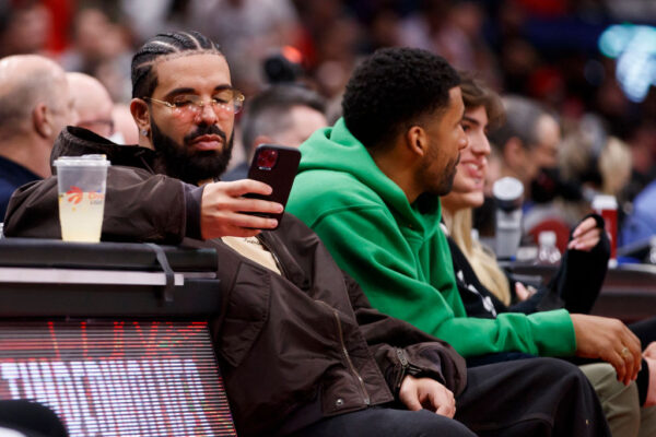 TORONTO, ON - APRIL 28: Rapper Drake texts while watching Game Six of the Eastern Conference First Round between the Toronto Raptors and the Philadelphia 76ers at Scotiabank Arena on April 28, 2022 in Toronto, Canada. NOTE TO USER: User expressly acknowledges and agrees that, by downloading and or using this Photograph, user is consenting to the terms and conditions of the Getty Images License Agreement. (Photo by Cole Burston/Getty Images)